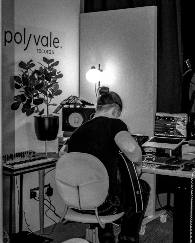 Studio Polyvale z logo na ścianie - praca przy biurku, zdjęcie czarno-białe